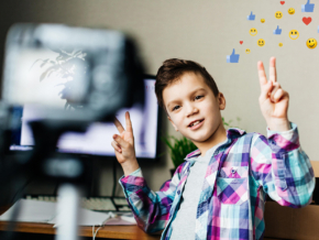 a child blogger takes pictures of himself on a camera, shows a like, holds a box in his hands, blog, video recording at home for a blog